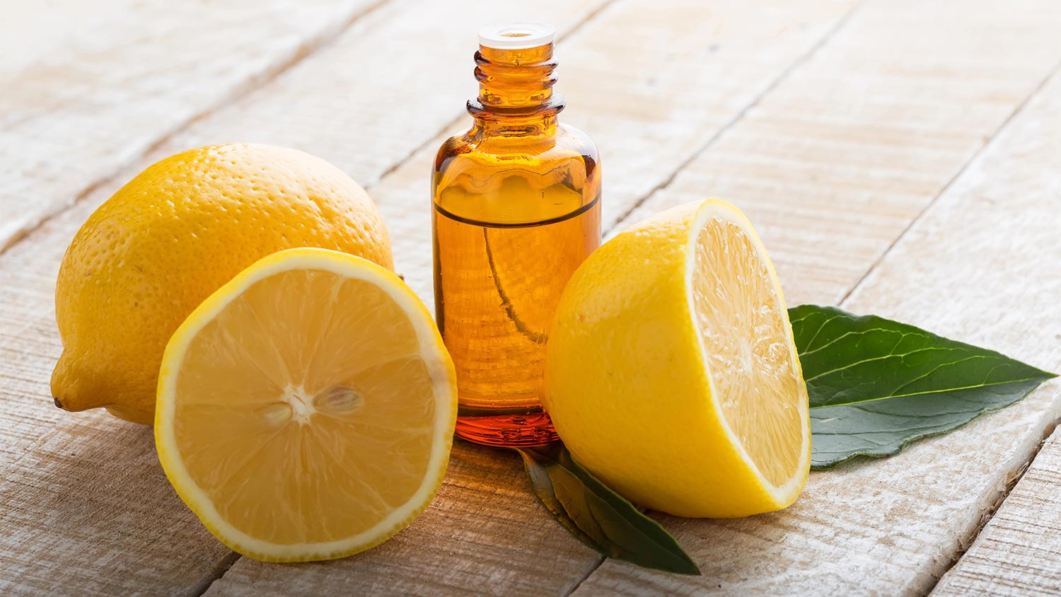 Bottle of 5-Fold Lemon Essential Oil Next to Freshly Cut Lemons